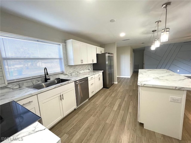 kitchen with decorative light fixtures, stainless steel appliances, white cabinetry, a sink, and a kitchen island