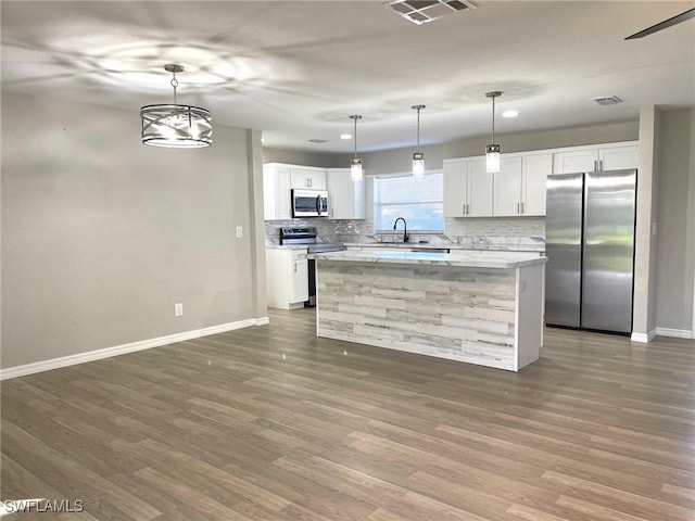 kitchen featuring a kitchen island, white cabinetry, hanging light fixtures, appliances with stainless steel finishes, and a chandelier