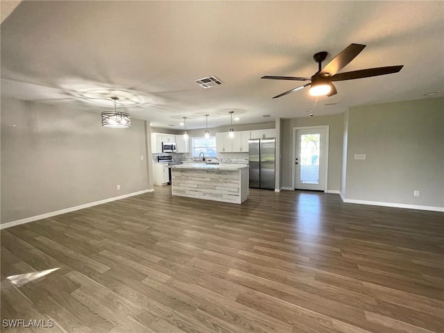 unfurnished living room with ceiling fan, sink, dark hardwood / wood-style floors, and a healthy amount of sunlight