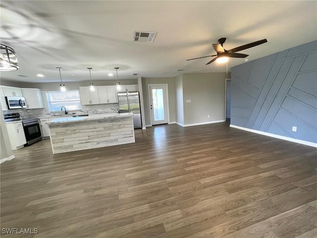 kitchen featuring a center island, decorative light fixtures, white cabinetry, stainless steel appliances, and tasteful backsplash