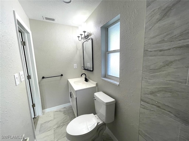 bathroom featuring a textured ceiling, toilet, and vanity