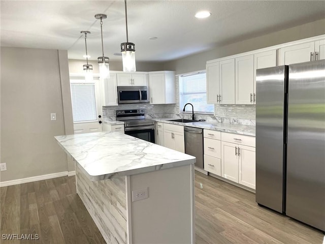 kitchen featuring pendant lighting, a center island, sink, white cabinetry, and appliances with stainless steel finishes