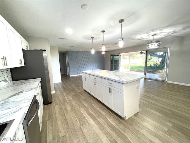 kitchen with white cabinetry, light hardwood / wood-style flooring, a center island, and decorative light fixtures