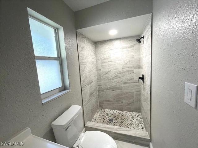 bathroom featuring tiled shower and toilet