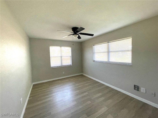 unfurnished room with a wealth of natural light, baseboards, and wood finished floors