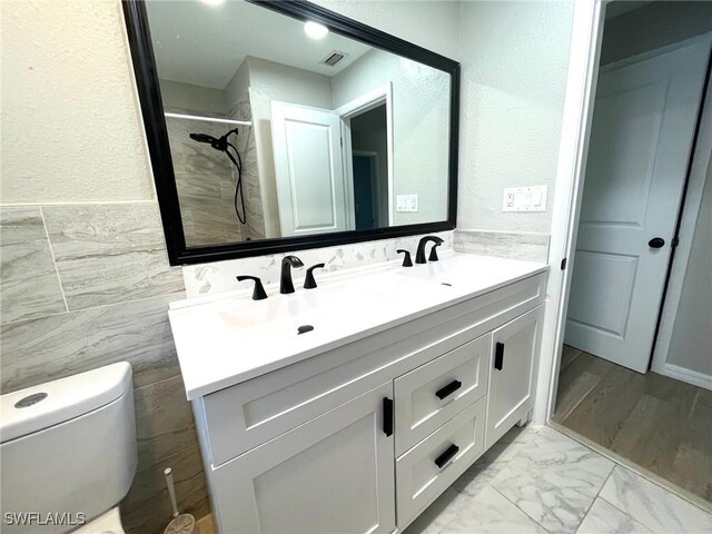 bathroom with toilet, vanity, and tile walls