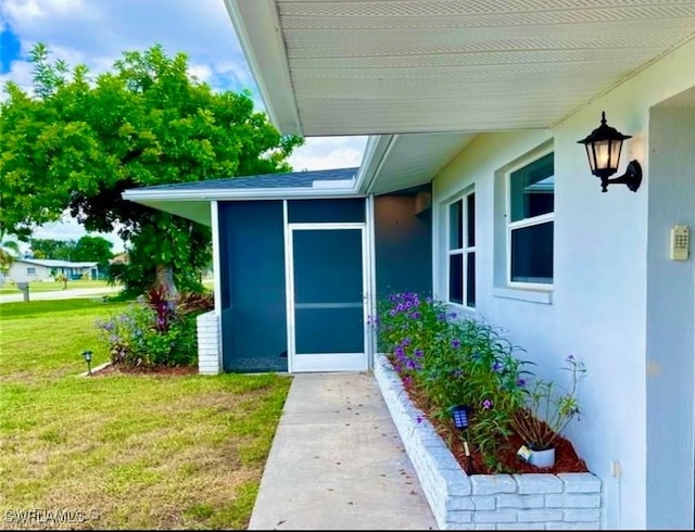 view of exterior entry with a yard and stucco siding