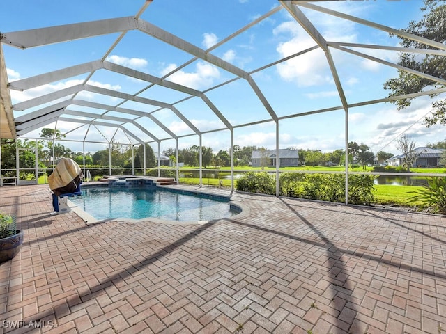 view of pool featuring glass enclosure, a patio area, a water view, and an in ground hot tub