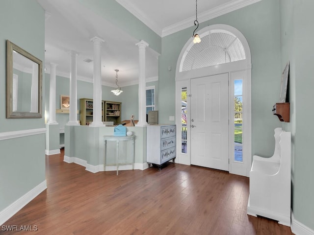 foyer entrance featuring decorative columns, crown molding, and dark wood-type flooring