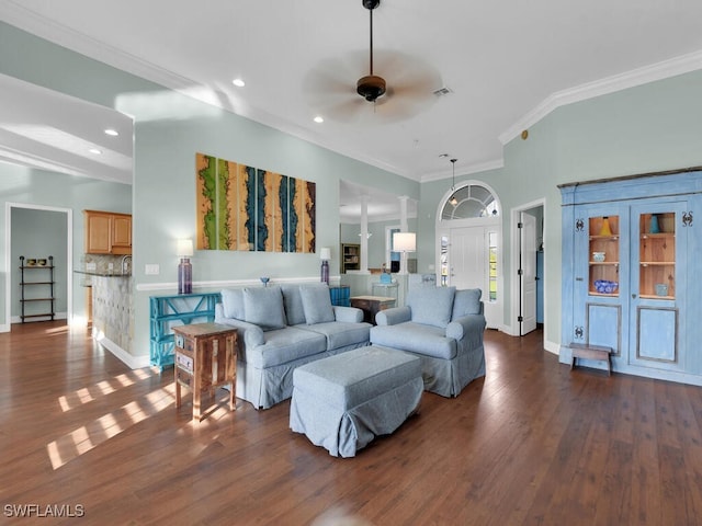 living room featuring ceiling fan, crown molding, dark wood-type flooring, and decorative columns