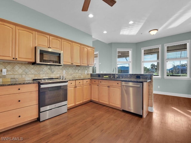 kitchen with light brown cabinets, dark stone counters, sink, wood-type flooring, and stainless steel appliances