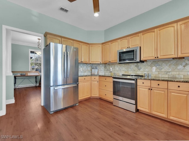 kitchen featuring light stone countertops, appliances with stainless steel finishes, backsplash, crown molding, and hardwood / wood-style floors