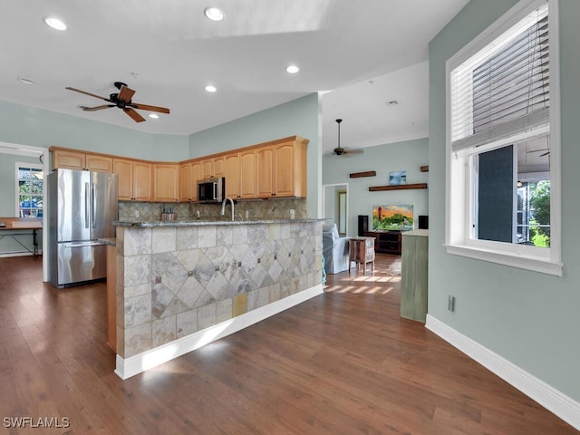 kitchen featuring ceiling fan, dark hardwood / wood-style floors, kitchen peninsula, light brown cabinetry, and appliances with stainless steel finishes