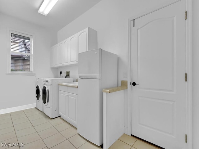 washroom featuring washer and clothes dryer, light tile patterned flooring, and cabinets