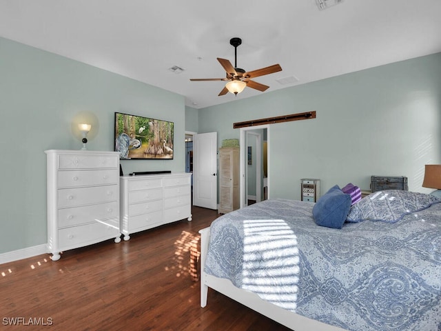 bedroom with ceiling fan, dark hardwood / wood-style floors, and a barn door