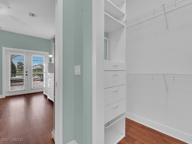 walk in closet with french doors and dark hardwood / wood-style floors