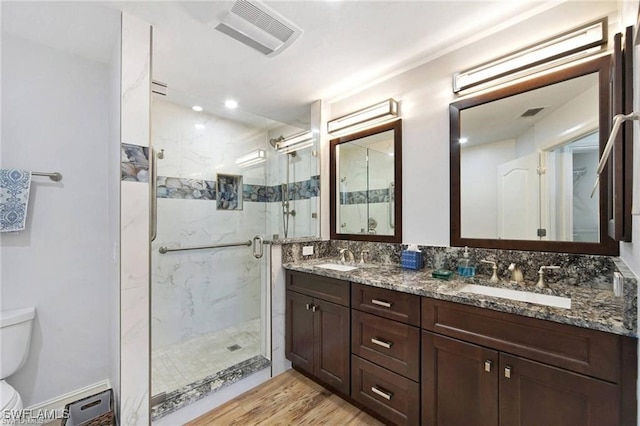 bathroom with toilet, vanity, wood-type flooring, and a shower with door