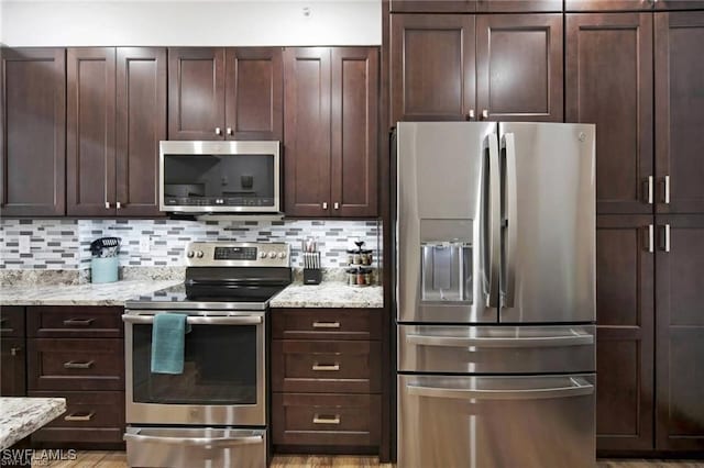 kitchen featuring dark brown cabinetry, stainless steel appliances, backsplash, and light stone countertops