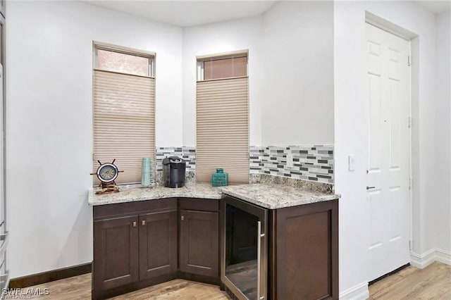 kitchen with dark brown cabinetry, light hardwood / wood-style floors, beverage cooler, and tasteful backsplash