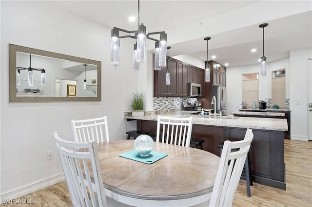 dining space with light wood-type flooring and sink