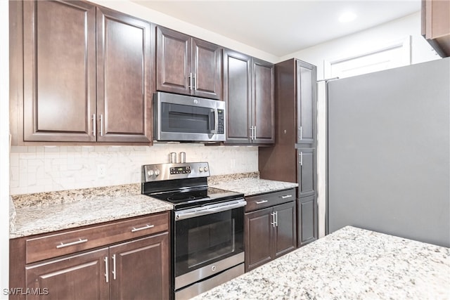 kitchen featuring light stone counters, tasteful backsplash, appliances with stainless steel finishes, and dark brown cabinets