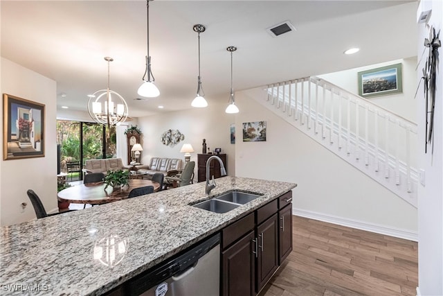 kitchen with light hardwood / wood-style floors, sink, stainless steel dishwasher, light stone countertops, and pendant lighting