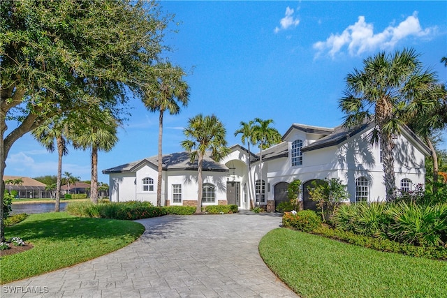 view of front facade with decorative driveway, a front yard, and stucco siding