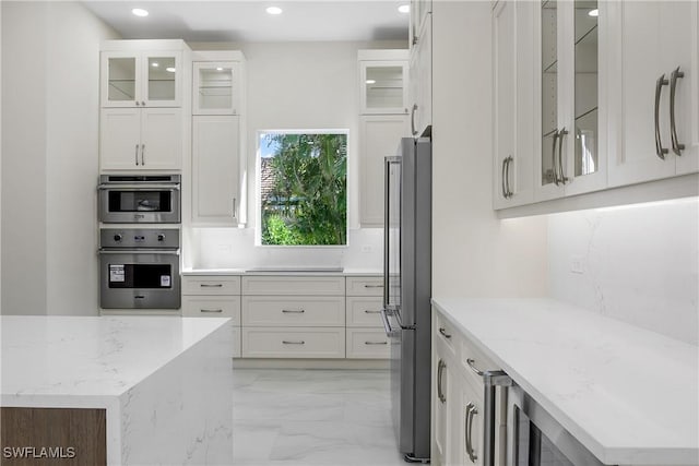 kitchen with light stone countertops, white cabinetry, and appliances with stainless steel finishes