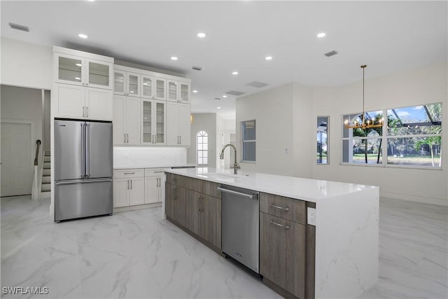 kitchen featuring a kitchen island with sink, sink, white cabinets, and stainless steel appliances