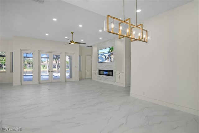 unfurnished living room featuring ceiling fan, a large fireplace, and french doors