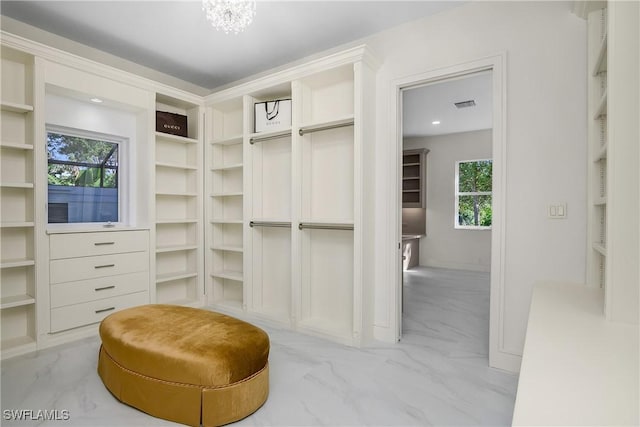 spacious closet featuring a notable chandelier