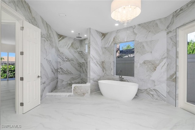 bathroom with an inviting chandelier, separate shower and tub, tile walls, and a healthy amount of sunlight