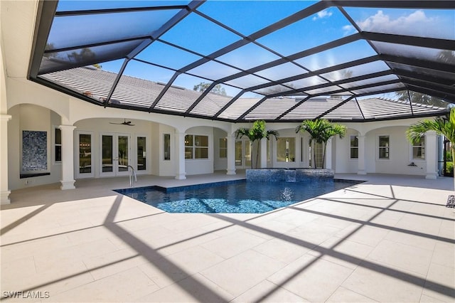 view of pool with glass enclosure, pool water feature, french doors, and a patio