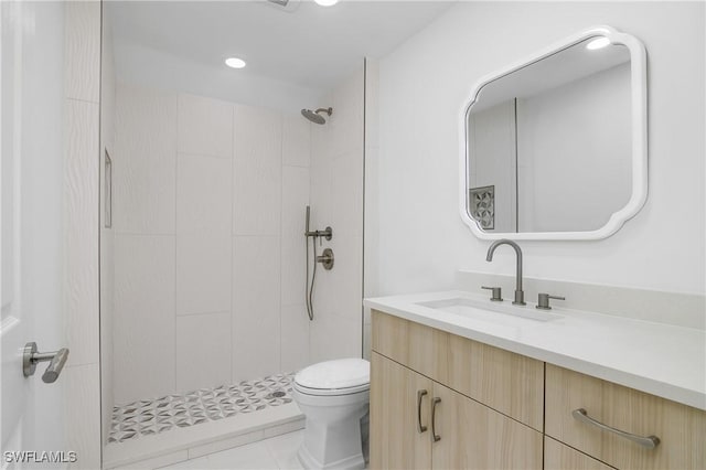 bathroom with a tile shower, tile patterned floors, vanity, and toilet