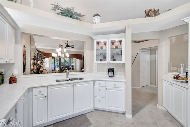 kitchen with backsplash, light tile patterned flooring, sink, and white cabinets