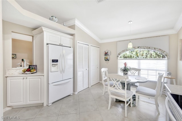 tiled dining area featuring crown molding and vaulted ceiling