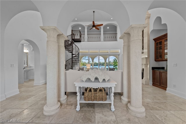 interior space with ceiling fan, decorative columns, and a high ceiling