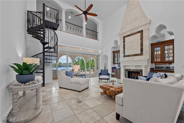 living room with a high end fireplace, high vaulted ceiling, sink, and ceiling fan