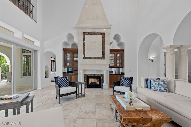 tiled living room with ornate columns, high vaulted ceiling, and a fireplace