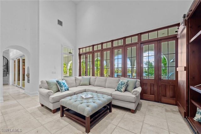 living room with a barn door and a high ceiling