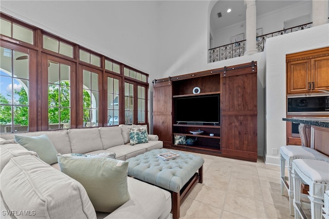 living room featuring a barn door, a high ceiling, and light tile patterned floors