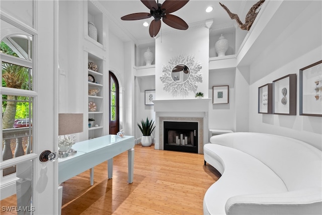 office area featuring ceiling fan, wood-type flooring, a high ceiling, built in shelves, and crown molding