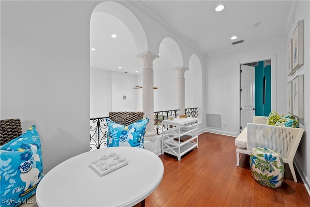 living area featuring ornamental molding, hardwood / wood-style flooring, and ornate columns