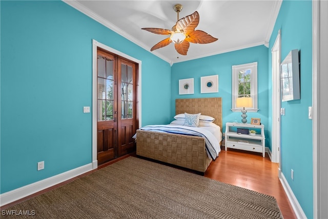 bedroom featuring ceiling fan, crown molding, wood-type flooring, and multiple windows