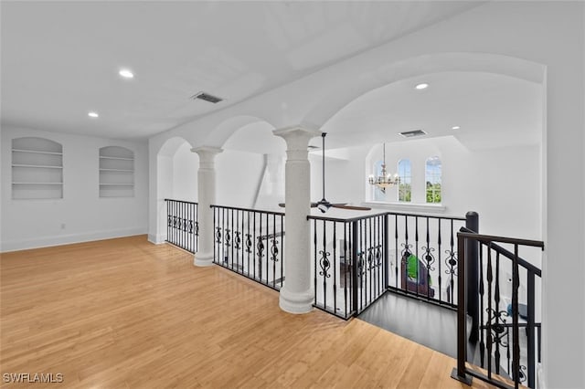 hall featuring hardwood / wood-style floors, a chandelier, and built in shelves