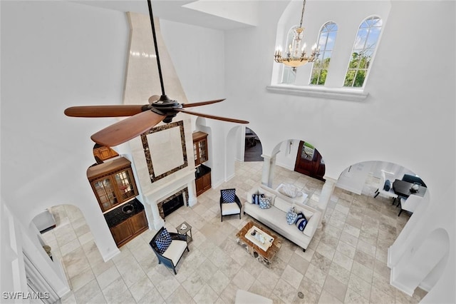 living room featuring ceiling fan with notable chandelier and ornate columns