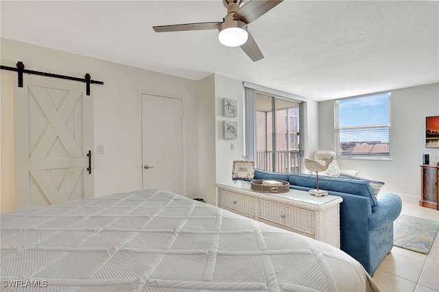 bedroom with ceiling fan, a textured ceiling, light tile patterned floors, and a barn door