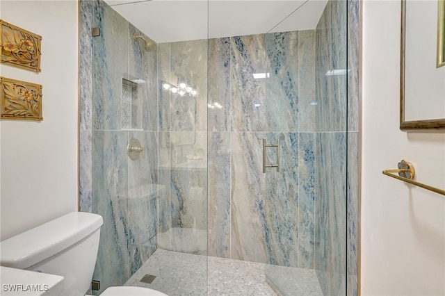 bathroom featuring a shower with door and toilet