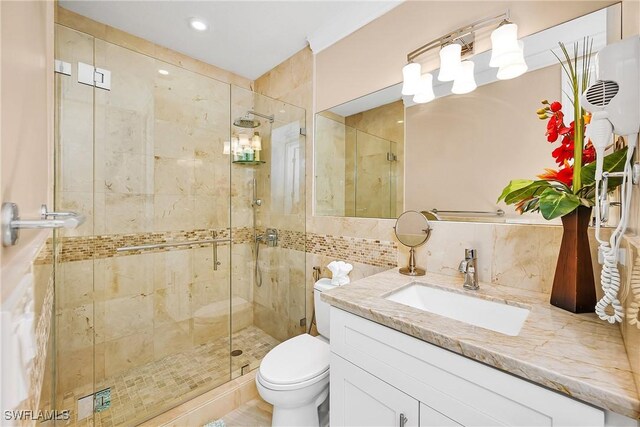 bathroom with tasteful backsplash, a shower with door, vanity, and toilet