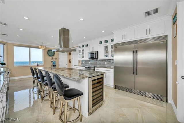 kitchen featuring a center island, stainless steel appliances, backsplash, island range hood, and white cabinets